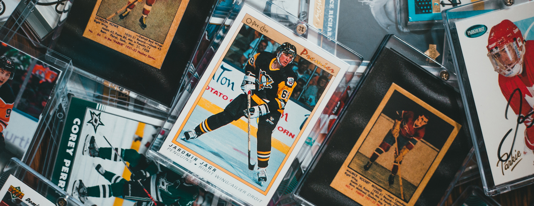 The Future of PSA Grading: Innovations and Predictions Sports cards featuring Jaromir Jagr, Gordon Howe, Corey Perry, and Maurice 'Rocket' Richard, with other cards stacked behind.